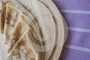 Baked pancakes on lilac tablecloth