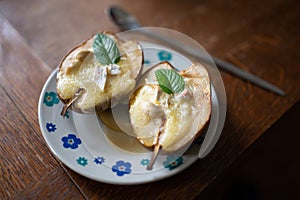 Baked pear dessert with cheese on a plate and a mint leaf