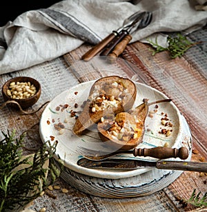 Baked pears cut in half with ricotta, granola, pine nuts on ceramic plate