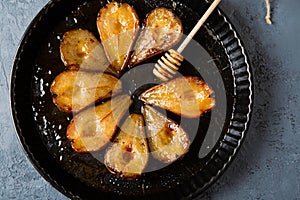 Baked pears with honey in a dark round baking tray