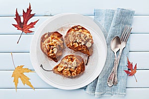 Baked pears with ricotta, walnuts, honey and cinnamon in plate on a blue vintage table from above. Delicious autumn dessert.