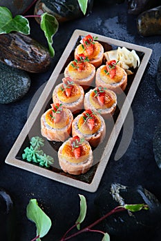 Baked Philadelphia rolls with strawberries and salmon. Traditional Japanese food. Vertical photo on a black background