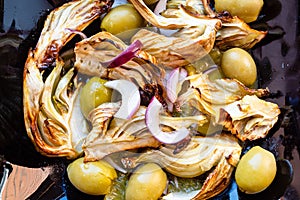 Baked pieces of fennel stalk with olives close up