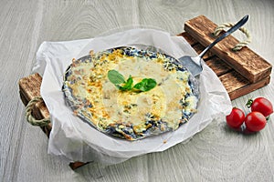 Baked pizza with 4 types of cheese, white sauce and on a black wooden background in a composition with ingredients. black cake.