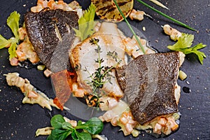 Baked plaice fillet with vegetables and sauce close-up on a bla