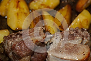 Photo of baked pork ribs and potatoes in oil and paprika close-up
