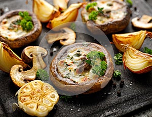 Baked portobello mushrooms stuffed with cheese and herbs on a black background, close-up. photo
