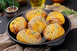 Baked potato with herbs on black background. Vegan food.