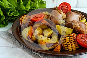 Baked potato with pieces roast goose, vegetables and corn grill