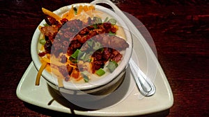 Baked Potato Soup On Fancy White Plate Served On Wood Table