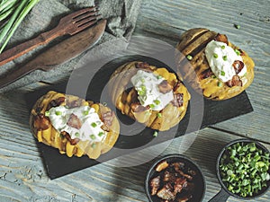 Baked potato stuffed with cheese, bacon and sour cream. loaded hasselback potatoes