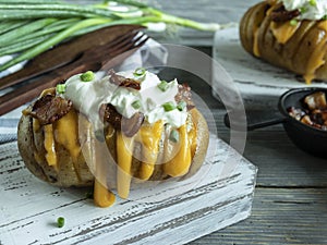 Baked potato stuffed with cheese, bacon and sour cream. loaded hasselback potatoes