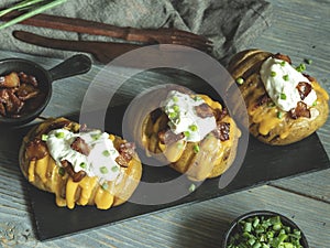 Baked potato stuffed with cheese, bacon and sour cream loaded hasselback potatoes