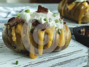 Baked potato stuffed with cheese, bacon and sour cream loaded hasselback potatoes