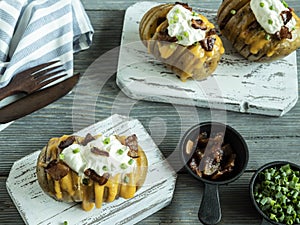 Baked potato stuffed with cheese, bacon and sour cream, loaded hasselback potatoes