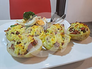 Food baked potatoes with cheese, accompanied by vegetales and harboiled eggs. photo