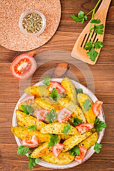 Baked potatoes in a peel with tomatoes in a plate and herbs