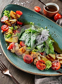 Baked potatoes with salad and tomatoes in plate on wooden background. Healthy vegan food, clean eating, dieting, close up