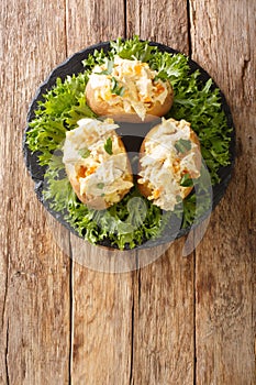 Baked potatoes stuffed with coronation chicken salad close-up on a slate board. Vertical top view