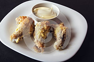 Baked poultry meat and mayonnaise on white plate. Delicious and dietary lunch or dinner on dark background