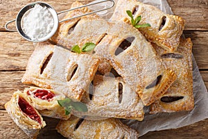 Baked puff cherry pies with powdered sugar and mint close-up. Horizontal top view