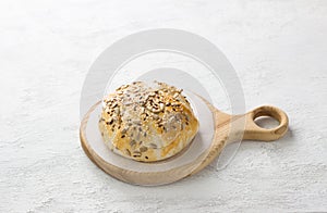Baked in puff pastry cheese sprinkled with seeds on a wooden board on a gray textured background