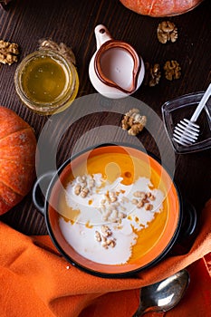 Baked pumpkin cream coup with, walnuts ,  coconut milk and natural honey served in nice bowl. served at wooden brown table with