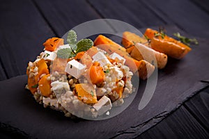 Baked pumpkin salad with feta cheese on black slate dish