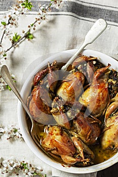 Baked quail stuffed with mushrooms, eggs and bread in a ceramic form on a wooden table.