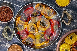 Baked red and yellow tomato and bell pepper. Tomatoes and bell peppers in a baking dish on a wooden table. A healthy and delicious