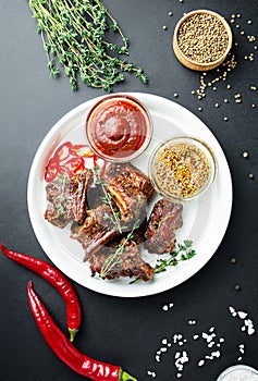 Baked ribs. Roasted pork ribs with spices and herbs on a dark background. Food background. View from above. Copy space