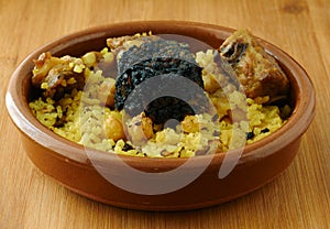 Baked rice in a pottery dish accompanied by pork, chickpeas, blood sausage, tomato and garlic. Traditional