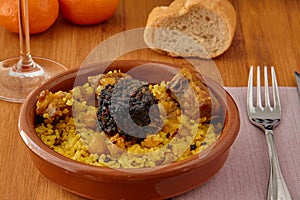 Baked rice in a pottery dish accompanied by pork, chickpeas, blood sausage, tomato and garlic. Traditional photo