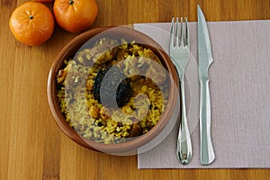 Baked rice in a pottery dish accompanied by pork, chickpeas, blood sausage, tomato and garlic. Traditional photo