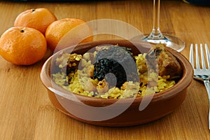 Baked rice in a pottery dish accompanied by pork, chickpeas, blood sausage, tomato and garlic. Traditional photo