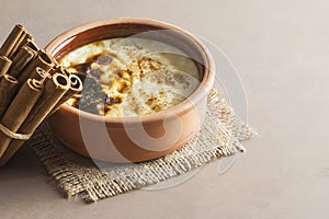 Baked rice pudding turkish dessert sutlac in earthenware casserole with cinnamon sticks