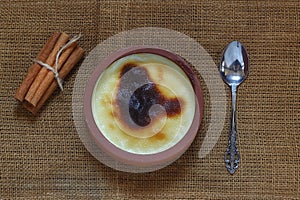 Baked rice pudding turkish dessert sutlac in earthenware casserole with cinnamon sticks