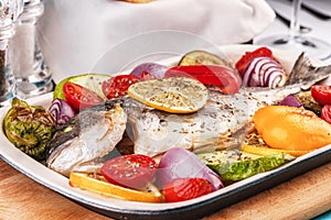 Baked river fish with lemon, vegetables, pepper and grilled tomatoes with spices.