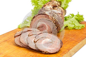 Baked rolled up pork belly on a cutting board closeup