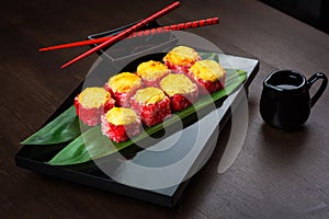 Baked rolls on the board with sauce and red chopsticks