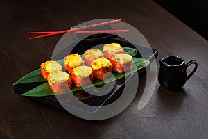 Baked rolls on the board with sauce and red chopsticks