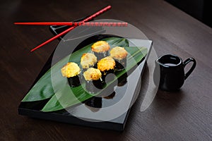 Baked rolls on the board with sauce and red chopsticks