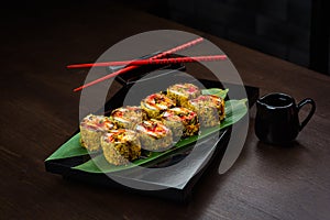 Baked rolls on the board with sauce and red chopsticks