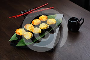 Baked rolls on the board with sauce and red chopsticks