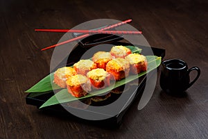 Baked rolls on the board with sauce and red chopsticks