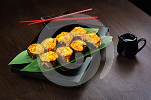 Baked rolls on the board with sauce and red chopsticks