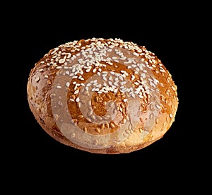 Baked round bun with sesame seeds isolated on black background