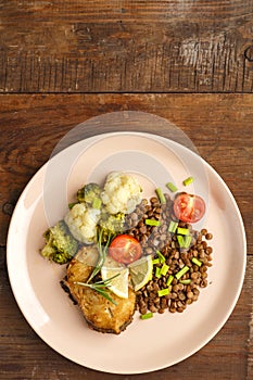 Baked rya with broccoli and lentils in a beige plate. Copy space.