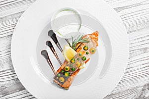 Baked salmon with cheese sauce, rosemary and lemon on wooden background close up.
