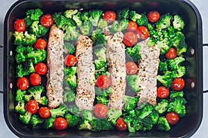 Baked salmon fillet with broccoli and tomato on frying tray, horizontal, top view